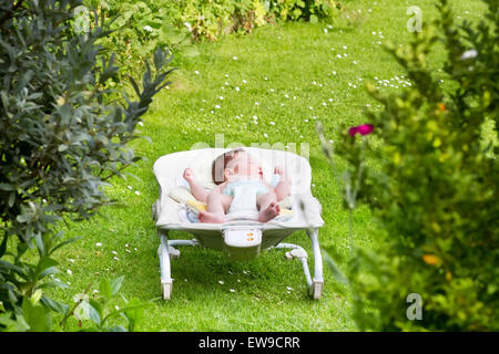 Neugeborene schlafen in einem Türsteher im Garten Stockfoto
