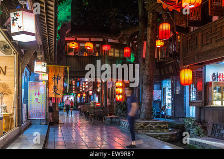 Menschen, die nachts in Chengdu, China, an Restaurants vorbei laufen Stockfoto