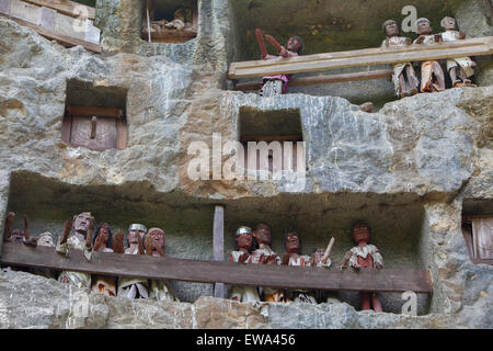 Steingrabeöffnungen und Holzraster auf einer Klippe an einer traditionellen Grabstätte in Lemo, Nord-Toraja, Süd-Sulawesi, Indonesien. Stockfoto