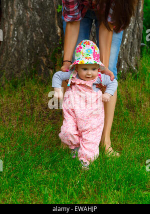 Kleines Mädchen macht die ersten Schritte mit Hilfe von Mama Stockfoto