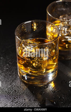 Brille von scotch Whisky mit Eis auf schwarzen Steintisch Stockfoto