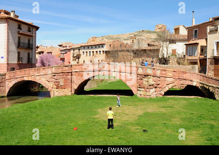 Zwei Kinder spielen Fußball mit der mittelalterlichen Brücke von Molina de Aragon als Ziel. Stockfoto