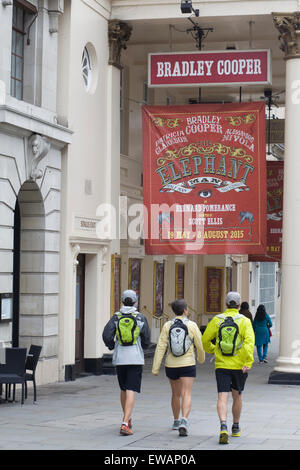 Touristen mit Rucksäcken auf zu Fuß in Richtung der Werbung für Bradley Coopers Elefant-Mann-show in London Stockfoto