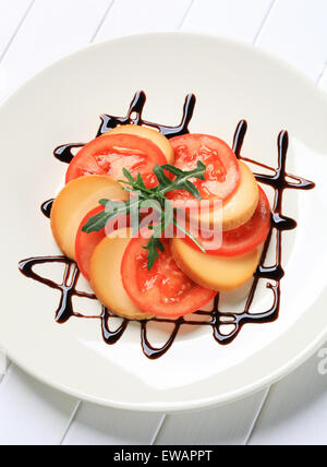 Tomatenscheiben und geräuchertem Käse garniert mit Balsamico-Essig Stockfoto