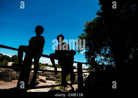 Kleiner Junge sitzt auf einem Zaun am Khone Phapheng Wasser fallen oder Mekong River im Süden von Laos, eines der größten champasak Stockfoto