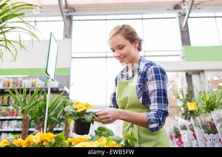 glückliche Frau mit Blumen im Gewächshaus Stockfoto