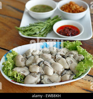 frische Austern mit Beilagen auf Schreibtisch aus Holz Stockfoto