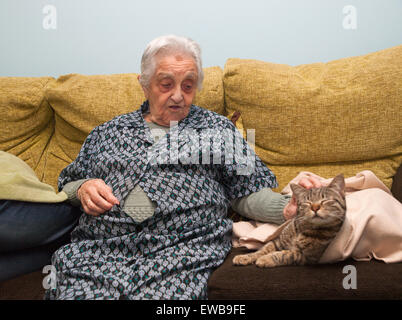 Ältere Frau streichelte ihre Katze im Haus. Stockfoto