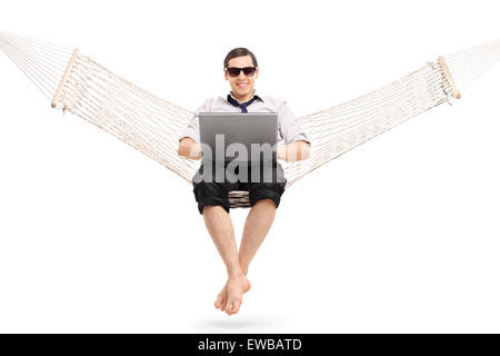 Entspannte junger Geschäftsmann auf einer Hängematte sitzen und arbeiten am Laptop isoliert auf weißem Hintergrund Stockfoto