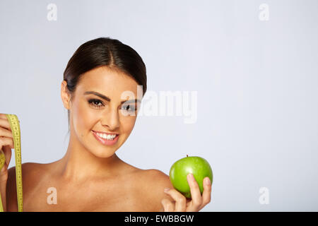 schöne junge Frau mit grünem Apfel und Maßnahme Klebeband Stockfoto