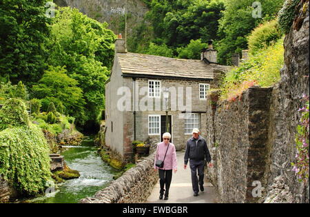 Hund Spaziergänger vorbei Stein Ferienhäuser auf dem Peakshole Wasser gebaut im Herzen von Castleton Dorf, Peak District Derbyshire UK GB EU Stockfoto