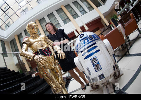 Dresden, Deutschland. 22. Juni 2015. Heidrun Waschhausen, Direktor des Steigenberger Hotel de Saxe, stellt inmitten Wachsfiguren von C-3PO (L) und R2-D2 von der Star Wars-Film-Franchise in Dresden, Deutschland, 22. Juni 2015. Madame Tussauds Berlin hat eine Sonderausstellung mit dem Titel "STAR WARS" in enger Zusammenarbeit mit Disney und Lucas Films eröffnet und hat eine Promotion-Tour durch Dresden, München, Stuttgart, Frankfurt, Köln und Essen vom 22. bis 25. Juni 2015 ins Leben gerufen. Foto: ARNO BURGI/Dpa/Alamy Live-Nachrichten Stockfoto