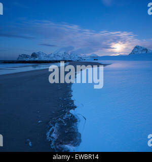 Mondaufgang über schneebedeckten Storsandnes Strand im Winter, Flakstadøy, Lofoten Inseln, Norwegen Stockfoto