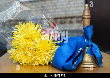 Alte Schulglocke mit gelben Blüten. Letzter Aufruf, Graduierung. Stockfoto