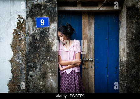 Eine junge Asiatin in der äußeren Tür eines ländlichen Hauses in Hanoi, Vietnam. Stockfoto