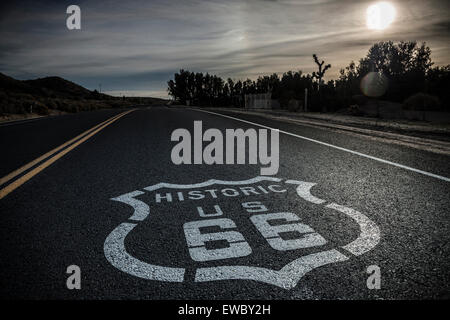 Klassisches Bild Historic Route 66 Schild gemalt auf der Autobahn. Launisch und dunkle Wolken, dunstige Sonne Stockfoto