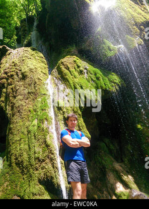 Mann, der von wunderschönen Wasserfall in Rumänien. Männliche Dschungel Wanderer unter Wasser im tiefen Wald. Stockfoto