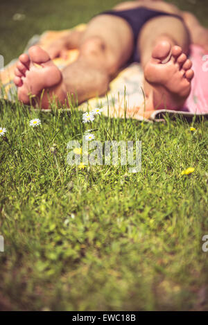 Foto eines jungen Mannes, der zum Sonnenbaden ist. Viel Grün im Vordergrund Stockfoto