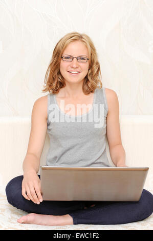Stilvolle junge Frau in schwarzen Gläsern mit laptop Stockfoto