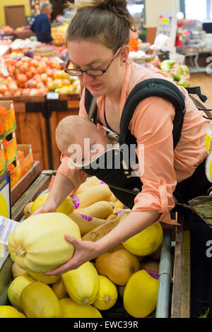 Wheat Ridge, Colorado - eine junge Frau, die Geschäfte in einem Supermarkt mit ihrem 11 Monate alten Sohn. Stockfoto