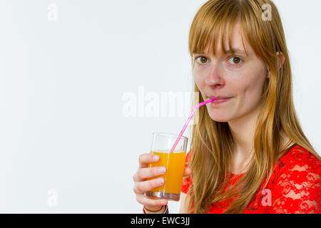 Rothaarige kaukasischen Teenager-Mädchen trinken Orangensaft mit Stroh isoliert auf weißem Hintergrund Stockfoto