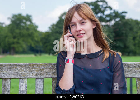 Kaukasische Teenager-Mädchen mit roten Haaren, telefonieren mit Handy in der Natur Stockfoto