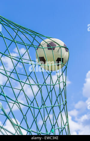 Schwarz / weiß Fußball im Tor-Netz mit blauem Himmel und weißen Wolken gefangen Stockfoto