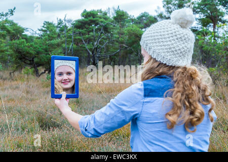 Niederländische Teenager Blondine mit langen Haaren in Spiegel mit Wald-Hintergrund Stockfoto