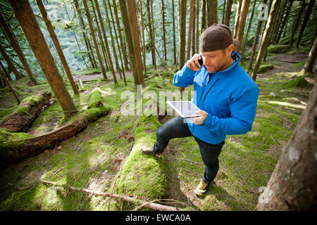 Ein Mann spricht am Telefon während der Arbeit an einem Tablet. Stockfoto