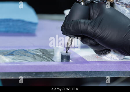 Eine elektrische Tätowiermaschine in schwarzer Tinte eingetaucht. Stockfoto