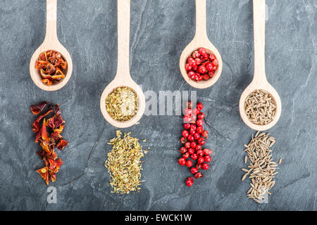 Verschiedenen Gewürzen auf schwarzem Hintergrund mit Holzlöffel Stockfoto