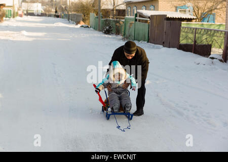 warm gekleidet in Overalls junge mit Großvater spielen in der Straße schneereiche winter Stockfoto