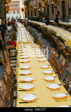 Siena gliedert sich in 17 Bezirke, bekannt als Contrade, und kämpfen sie, zehn von den Bezirken zu einer Zeit, in der zweimal ein Jahr, am 2. Juli und 16. August Pferderennen um den zentralen Platz Campo. Hier Einrichten eines langen Tischen für eines der Viertel der Nacht vor dem Palio-Pferderennen. Siena, Toskana. Italien. Juli. Stockfoto