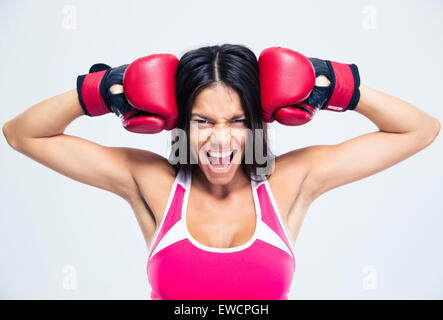 Fitness-Frau mit Boxhandschuhen schreien über grauen Hintergrund Stockfoto