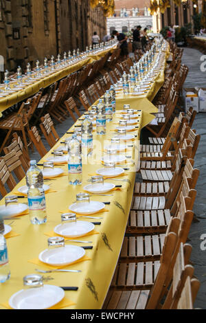 Siena gliedert sich in 17 Bezirke, bekannt als Contrade, und kämpfen sie, zehn von den Bezirken zu einer Zeit, in der zweimal ein Jahr, am 2. Juli und 16. August Pferderennen um den zentralen Platz Campo. Hier Einrichten eines langen Tischen für eines der Viertel der Nacht vor dem Palio-Pferderennen. Siena, Toskana. Italien. Juli. Stockfoto