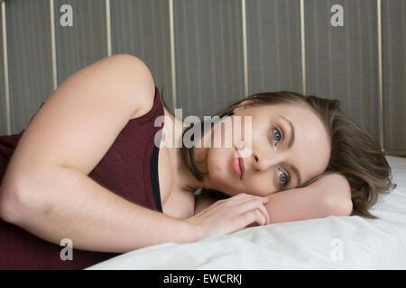 Glückliche junge Frau lächelnd im Bett Stockfoto