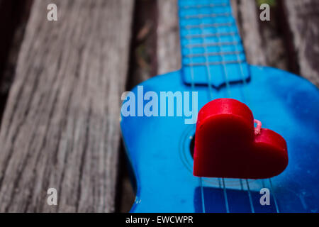 Rotes Herz in den Schatten auf einer einsamen Gitarre. Stockfoto