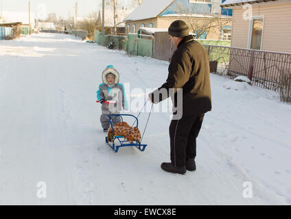 warm gekleidet in Overalls junge mit Großvater spielen in der Straße schneereiche winter Stockfoto