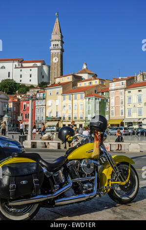 Eine gelbe Harley Davidson Motorrad in Tartini-platz geparkt mit St. George's Kirche hinter sich. Piran. Slowenien Stockfoto