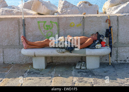 Ein junger Mann auf einer konkreten Bank eingeschlafen. Piran. Slowenien Stockfoto