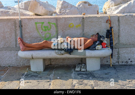 Ein junger Mann auf einer konkreten Bank eingeschlafen. Piran. Slowenien Stockfoto