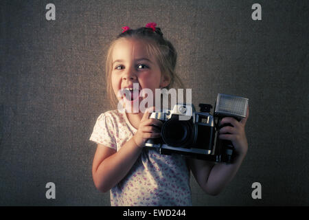 Das fröhliche Mädchen der Fotograf mit der Kamera in Händen. Es wird unter einem alten Foto stilisiert. Stockfoto