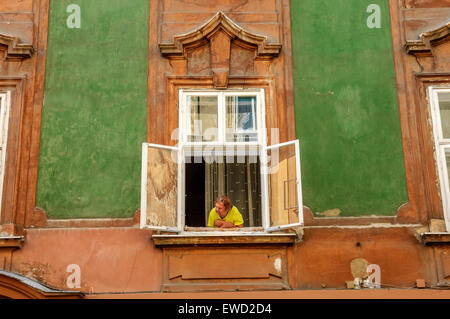 Eine ältere Frau, Blick aus dem Fenster ihrer Wohnung in der Altstadt von Ljubljana. Slowenien. Stockfoto