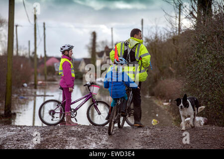 Eine Familie auf Fahrräder Haltestelle einen vorläufigen Damm zurückhalten Hochwasser im Dorf von Moorlandschaften, Somerset UK Stockfoto