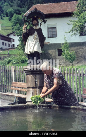 Frau im Wasser des Dorfbrunnen von Ladis 1977 Frau Wäscht Salat Salat waschen bin Dorfbrunnen von Ladis. Stockfoto