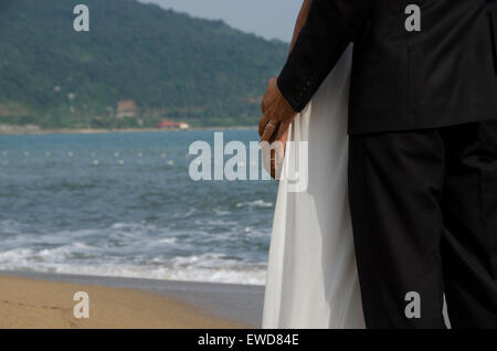 Liebenden Paare, die am Strand Hochzeitsfoto Händchenhalten lachende Interracial paar umarmt Stockfoto