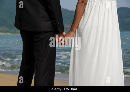 Liebenden Paare, die am Strand Hochzeitsfoto Händchenhalten lachende Interracial paar umarmt Stockfoto