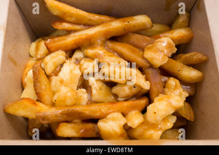 Poutine – eine kanadische Delikatesse aus Pommes frites oder Pommes Frites mit Soße und Käsequark, die auf dem Brick Lane Market in London angeboten wird Stockfoto