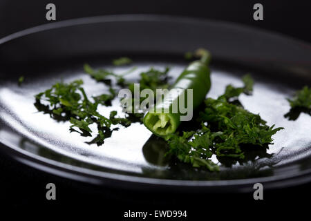 Scharfe Chilischoten auf dunkle Platte mit Petersilie Stockfoto