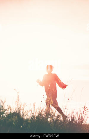 Frau läuft in die Freiheit durch Landschaft Feld, Silhouette der weiblichen Person, Doppelbelichtung, Vintage Retro-Ton-Effekt. Stockfoto